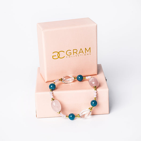 BubbleGum Bracelet placed on the edge of its pink box surrounded by a white background. 