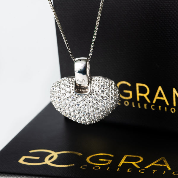 A sterling silver Carina necklace with a heart-shaped pendant covered in cubic zirconia, displayed on a branded box.