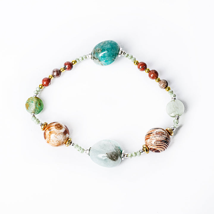 A close up view of multicolored beaded Clover bracelet with a gold plated stainless steel core, featuring various natural stones, standing in the center of the image against a white background. 