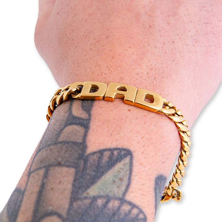 A 'DAD' bracelet on a wrist of a model with tattoos, showcasing real life look. 
