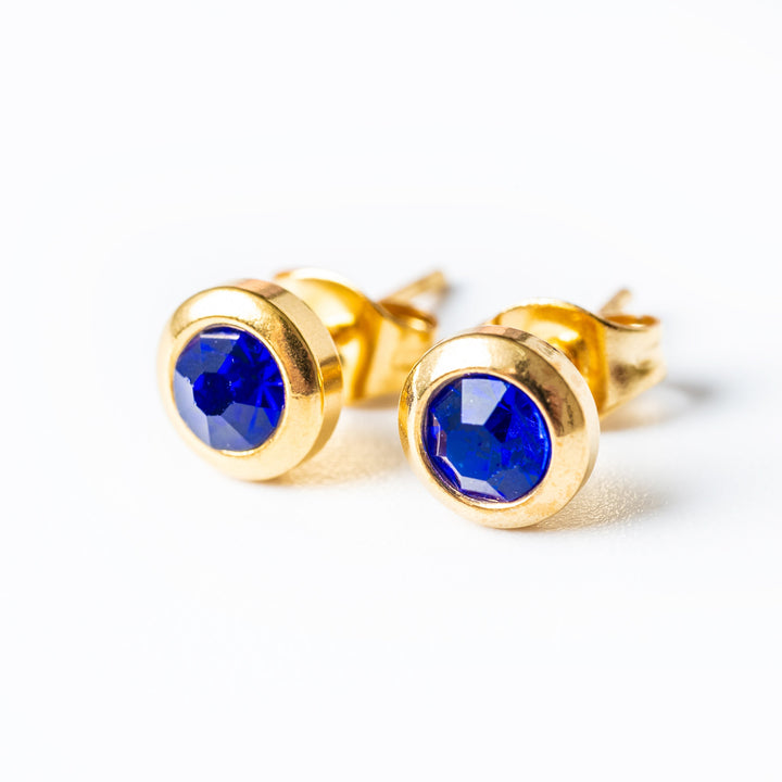 A close up view of Gabriella Gold Earrings wit a blue pendant 