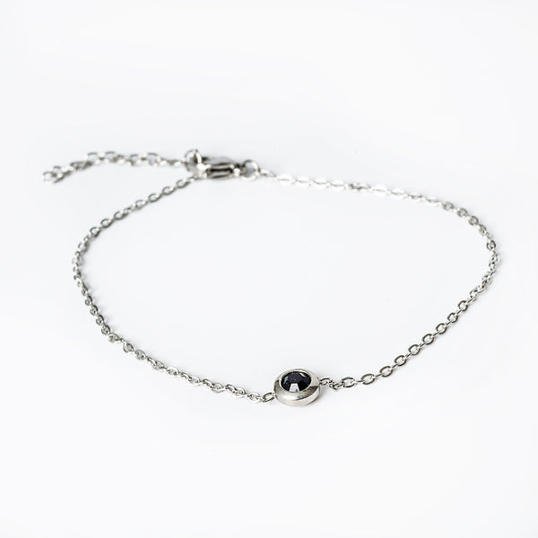 A silver bracelet with gold plating and a central cubic zirconia gemstone.