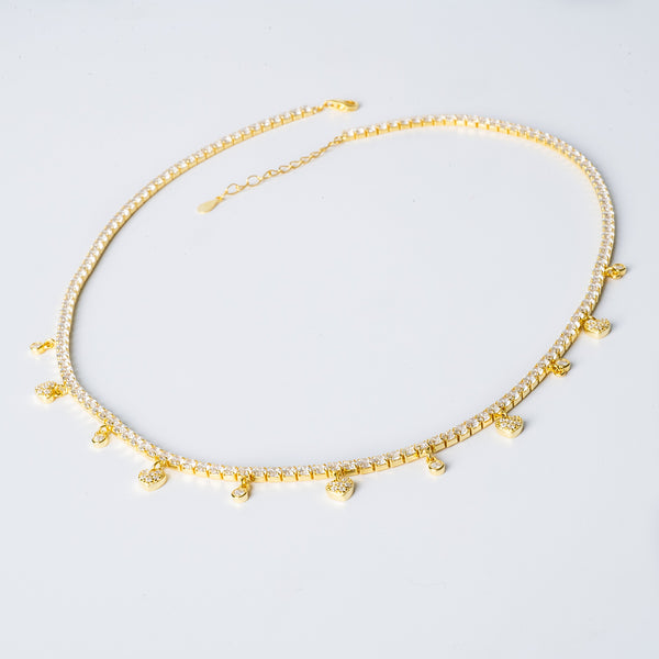 Gulia necklace with a yellow gold finish, featuring a series of round beads and a pair of small bell-shaped charms.