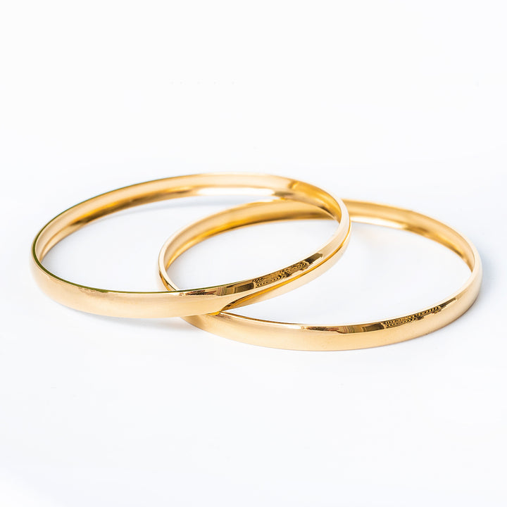 Two Kolina filli gold plated bangles on a white background