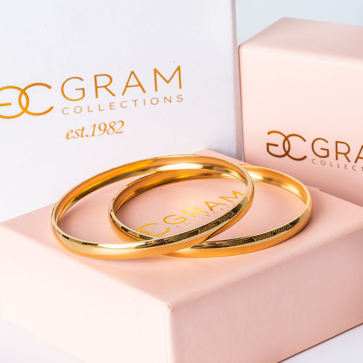 Two gold-plated Kolina Filli stainless bangles with a shiny finish, placed next to each other on a white background.