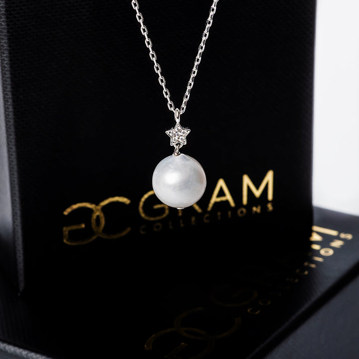 A close up view of Lina necklace standing in front of its box. 