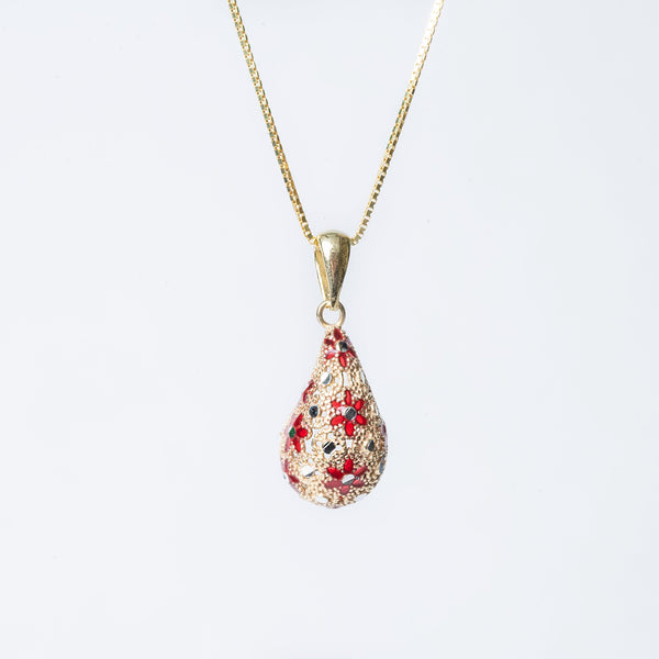 A sterling lucija necklace with a yellow gold chain and a teardrop-shaped pendant featuring red enamel.