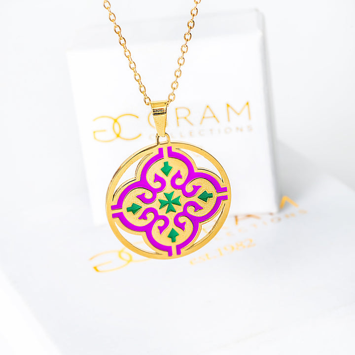 Gold Maduma necklace with a purple and green pendant on a white backgroun