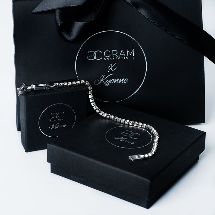 Silver Kyonne diamond tennis bracelet displayed on black branded boxes with gift packaging