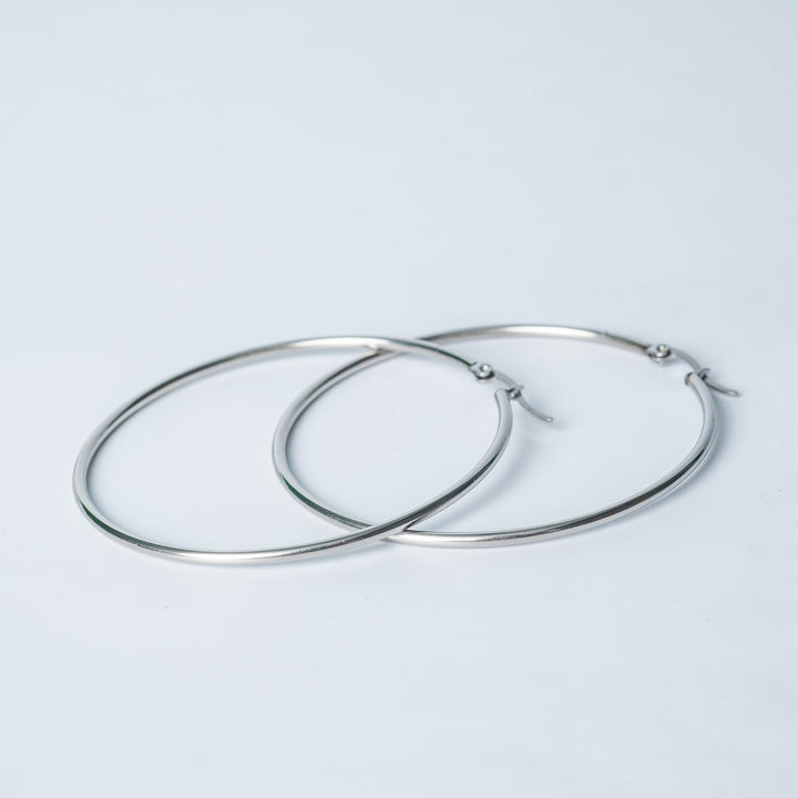 Silver Maya hoop earrings overlapping on a white background