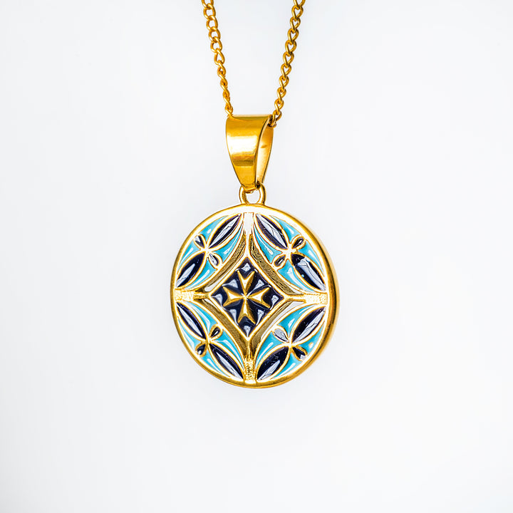 Gold pendant with blue and black design on a white background
