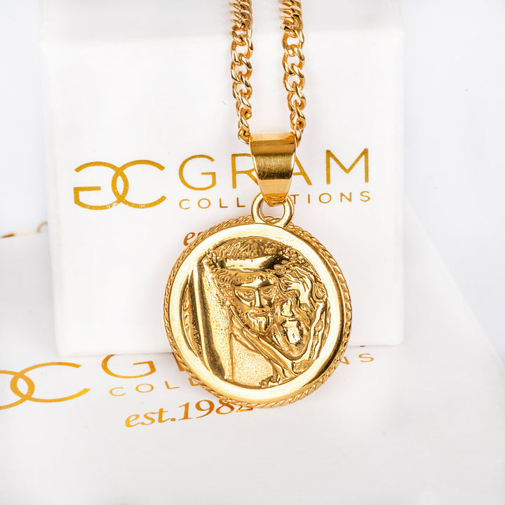 Redentur pendant attached to a chain, surrounded by its box. 