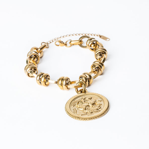 A Ta' Lira Bracelet gold-colored bracelet with a circular charm, made of stainless steel, displayed against a white background.