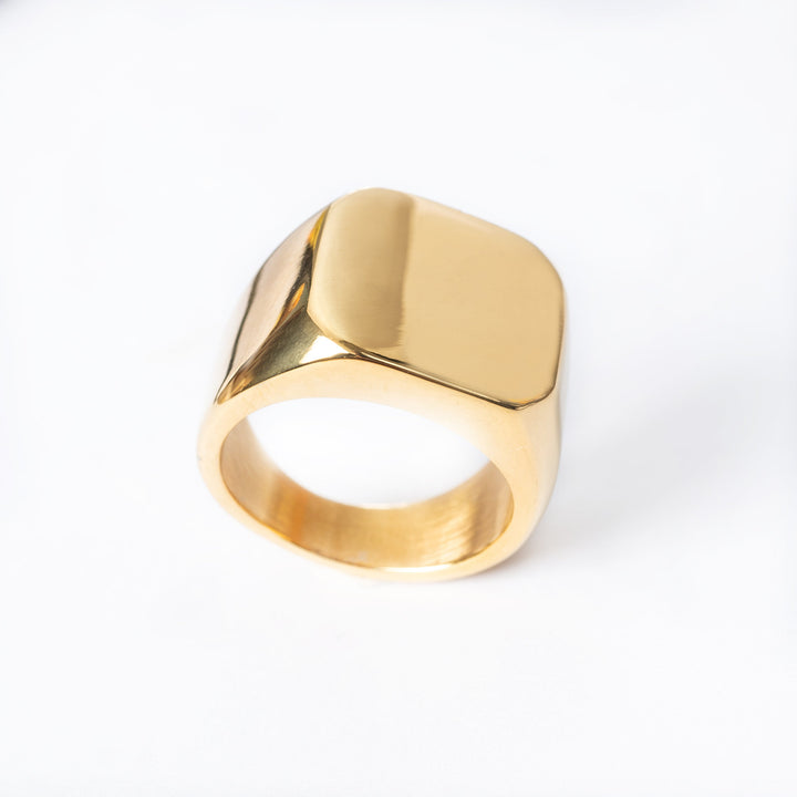 A gold-colored stainless steel signet ring with a polished finish