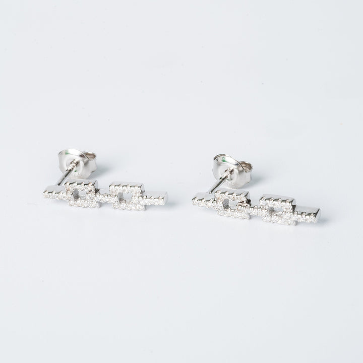 A pair of silver Alana earrings with cubic zirconia embellishments on a white background.