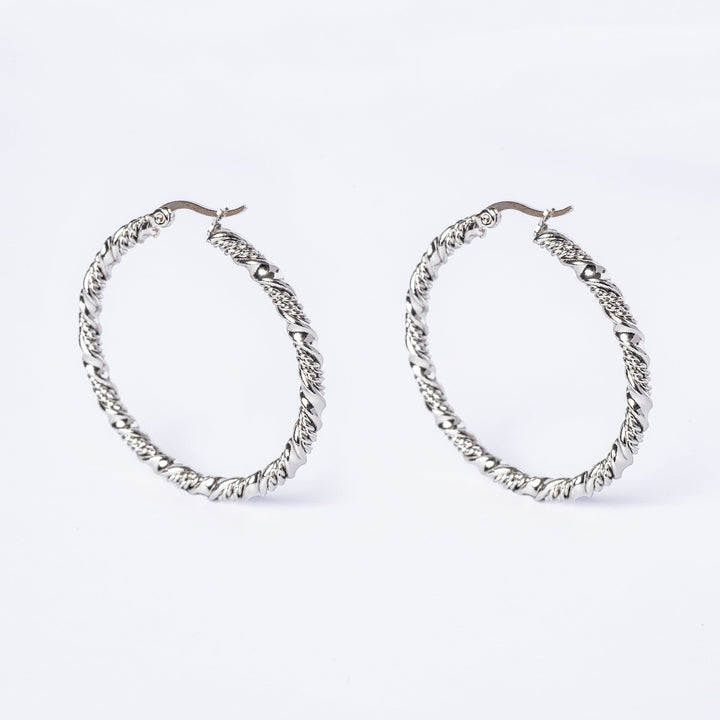 A pair of silver-colored stainless steel Amber hoop earrings on a white background