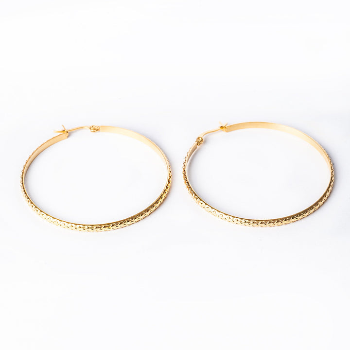 Anna gold earrings standing in the center of the image. 