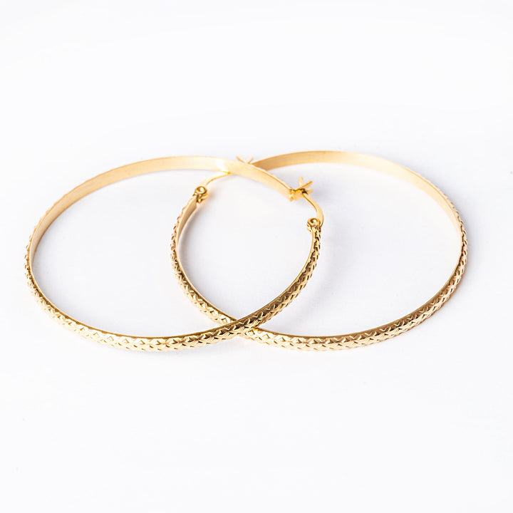 A pair of yellow gold hoop earrings with a textured surface, displayed against a white background.