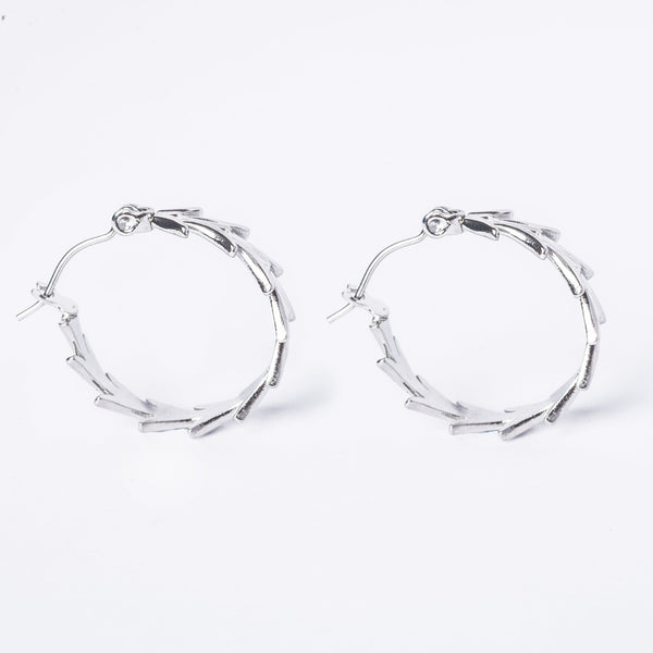 A pair of silver-colored stainless steel hoop earrings on a white background.