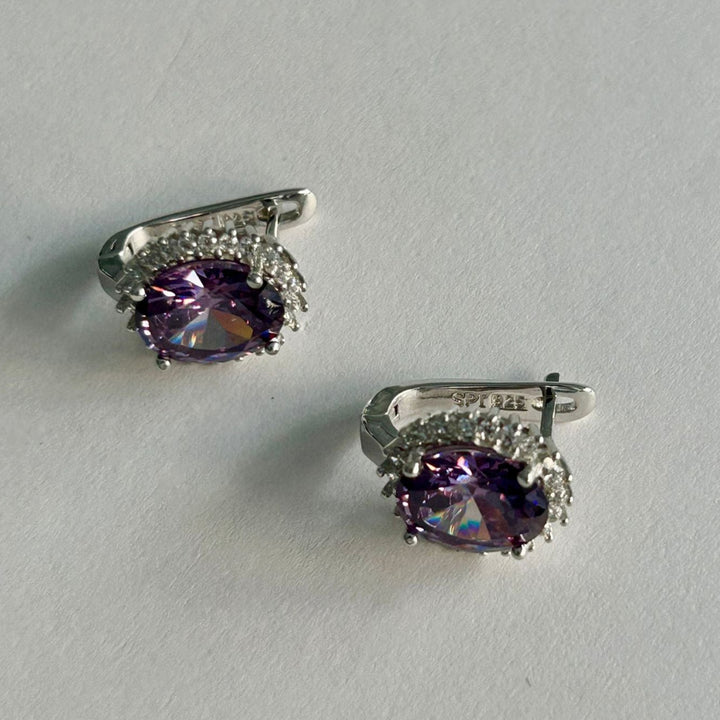A bird view of Kate Earrings purple stone colour standing in the center of the image against a white background. 