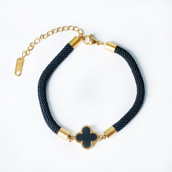 Black cord bracelet with a gold clover pendant and gold adjustable chain