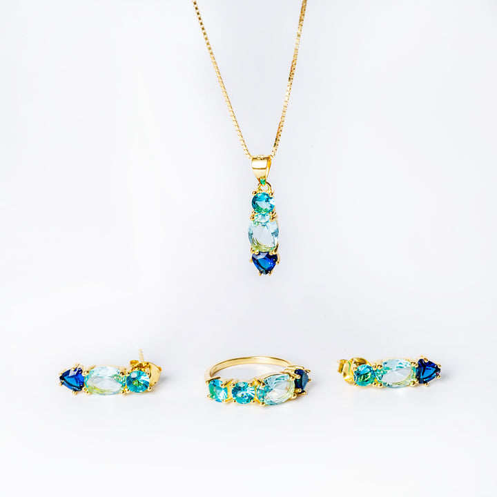 A set of jewelry including a pendant with blue and yellow cubic zirconia and a gold-colored chain, and a pair of earrings with blue and yellow cubic zirconia set in yellow gold-colored frames.