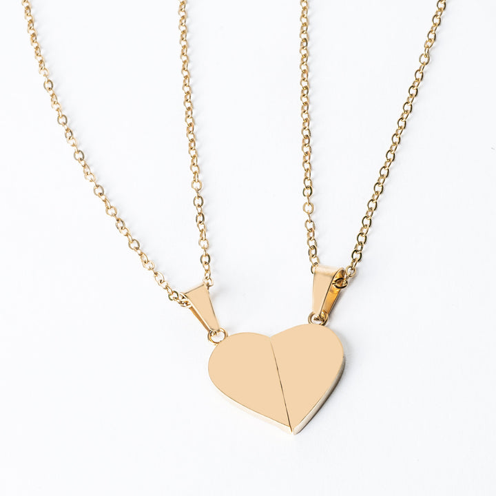Broken Heart placed next to each other, forming a shape, attached on its respectful chain, standing against a white background. 