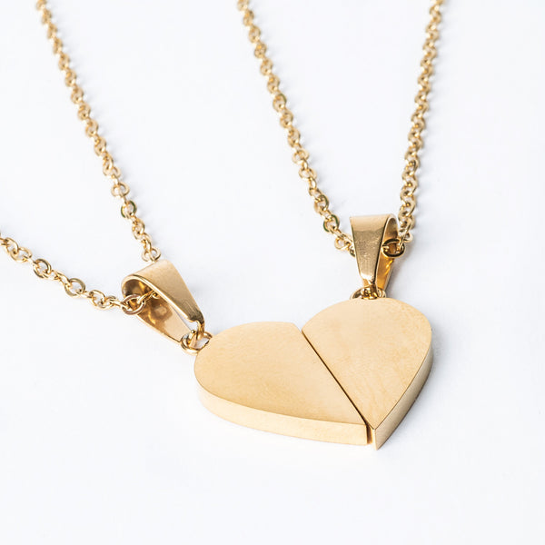 Two pieces of broken heart necklaces in yellow gold color, designed to be worn as a pair.
