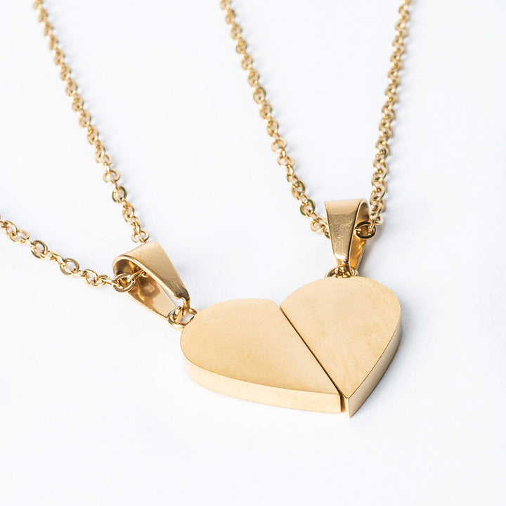 Two pieces of broken heart necklaces in yellow gold color, designed to be worn as a pair.