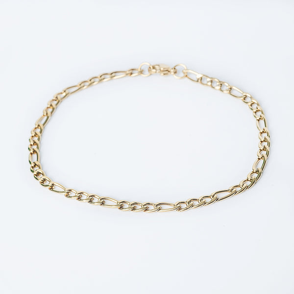 Calabria Bracelet in gold featuring a slim Figaro chain displayed on a white background