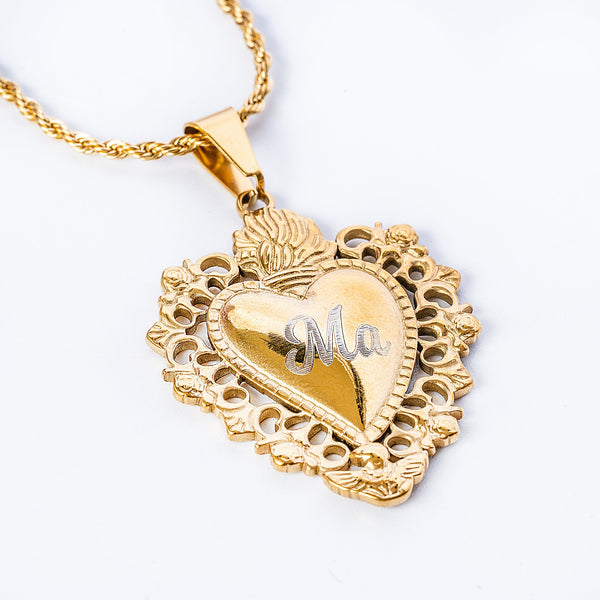 A stainless steel Cara Mum Necklace with a yellow gold finish pendant in the shape of a heart, featuring the "MA" words in the center. 