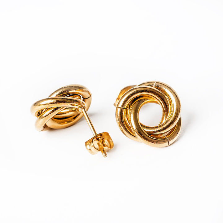 A close up view of Carment gold earring standing in the center of the image against a white background. 