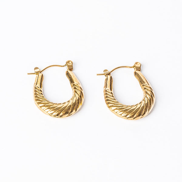 A pair of yellow gold hoop earrings with a textured surface on a white background.