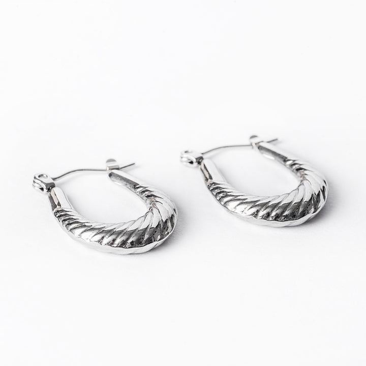 A pair of silver hoop earrings with a textured surface, displayed against a white background.