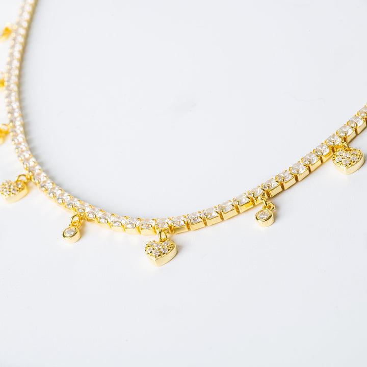 The Gulia necklace is shown in close-up, placed in the upper part of the image against a silver background