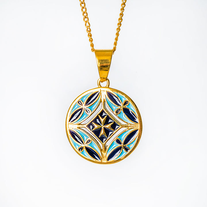 Gold necklace with a blue and black decorative pendant on a white background