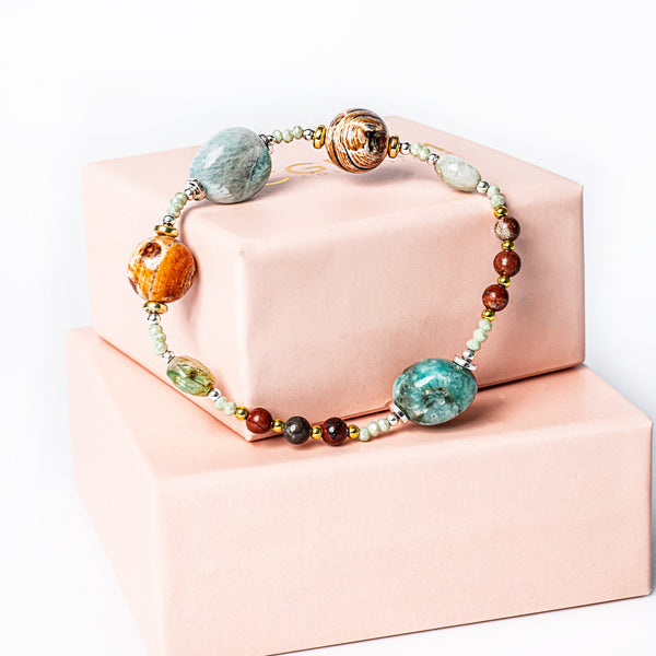 A clover bracelet placed on its uniquely designed box, standing all together against a white background. 