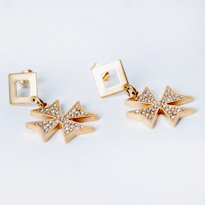 A side view of a Cross of the order Earrings standing in the center of the image.