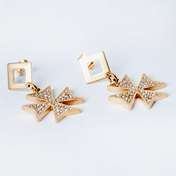 A pair of yellow gold cross-shaped earrings with intricate detailing and gemstone embellishments on a white background.