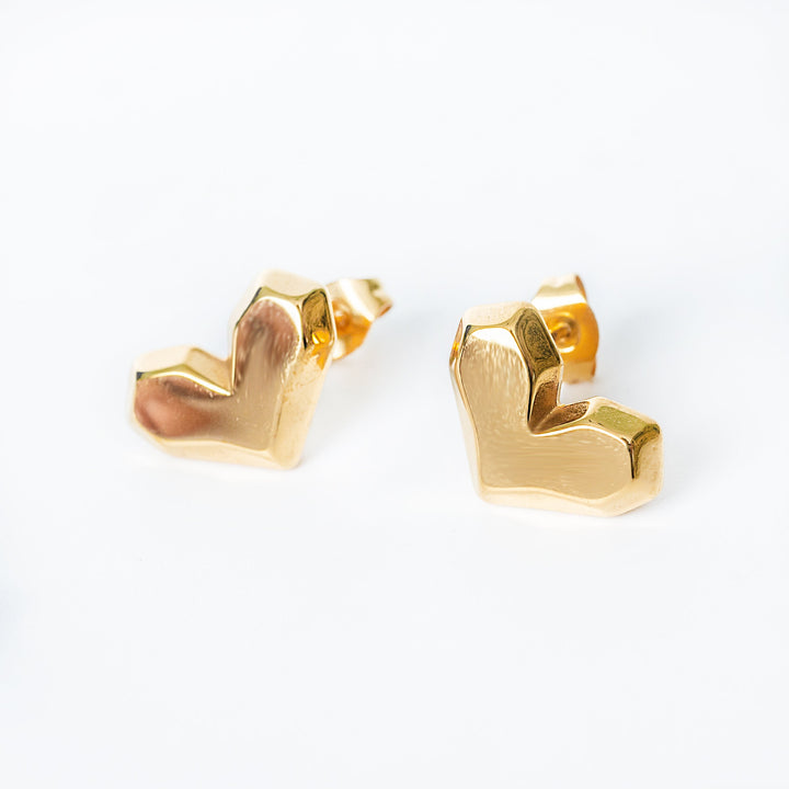 Danita gold stud earrings with faceted heart shaped design in a close up view