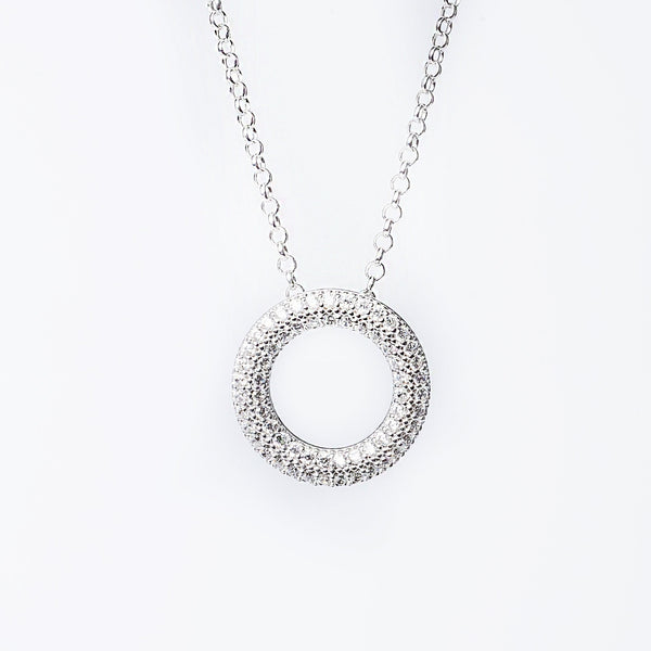 A sterling silver Delphine necklace with a round pendant featuring multiple cubic zirconia stones set within a metallic frame, attached to a chain.
