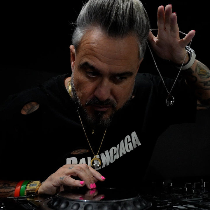 An dj wearing the dj necklae while playing the music on a podium. 
