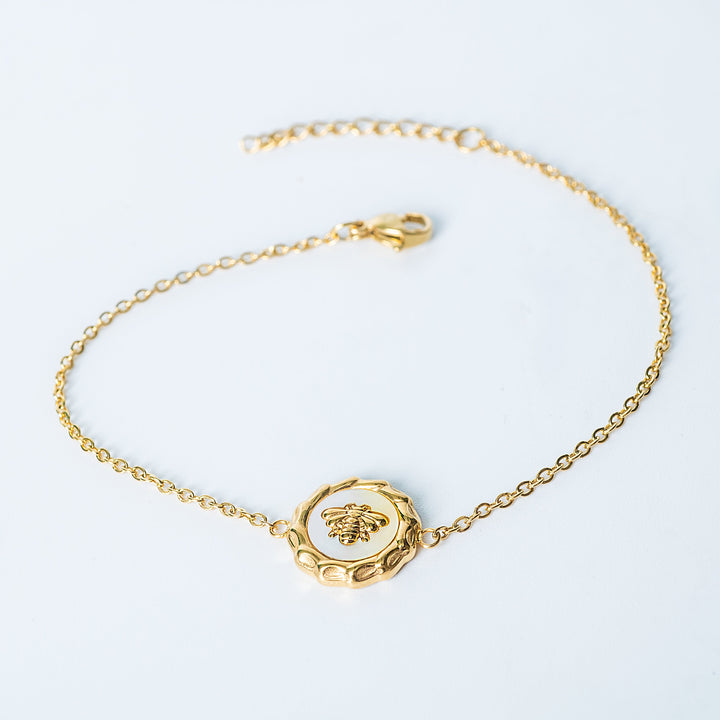 Gold Evelyn bracelet with a bee pendant displayed on a white background
