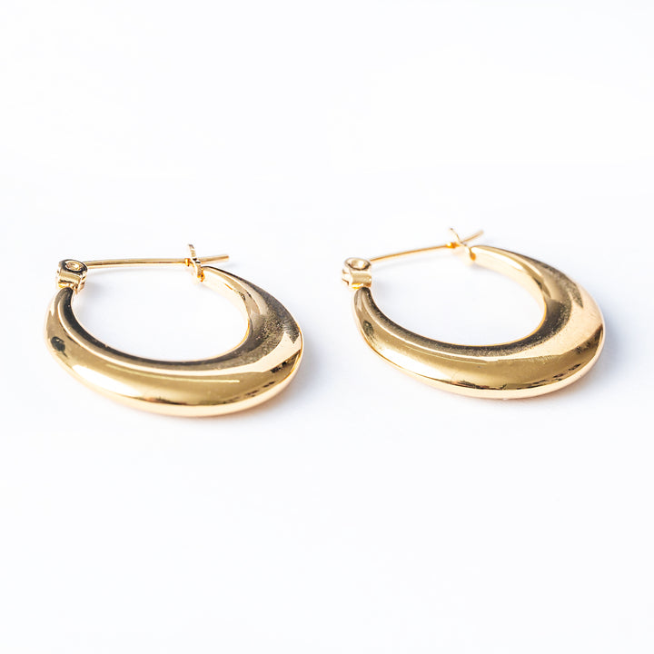 A side view of Yellow gold Evia earrings standing in the center of the image against a white background. 