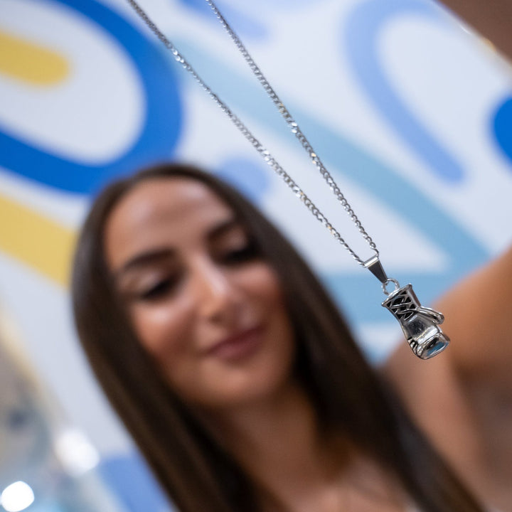 The female model holding  silver colour Boxer Necklace in her hands. 