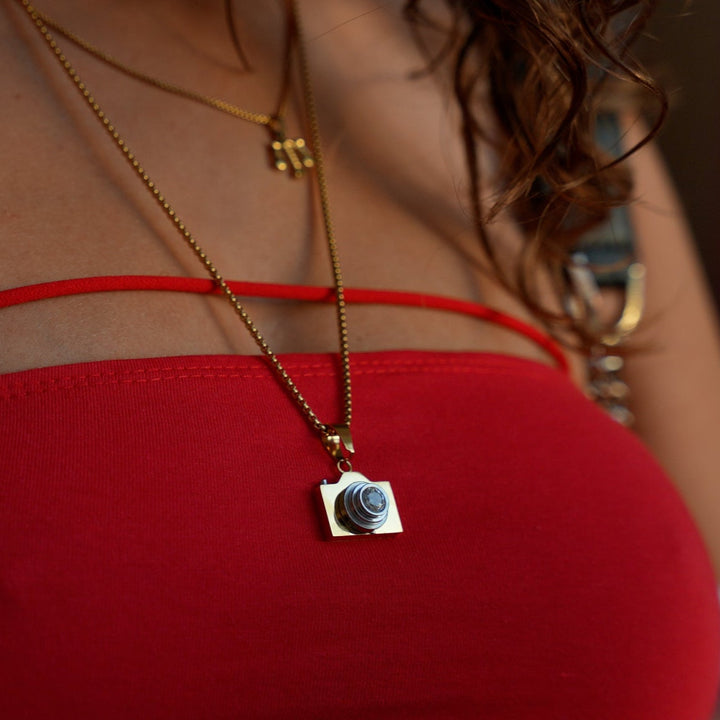 Female wearing The Photographer Necklace combined with her red dress. 