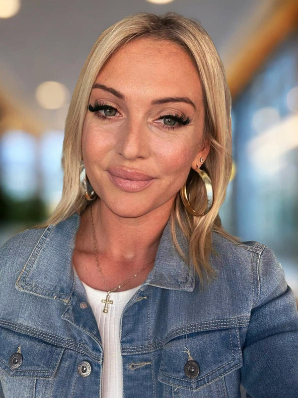 A model wearing yellow gold Filli Lixxi  earrings and a denim jacket with a cross necklace.
