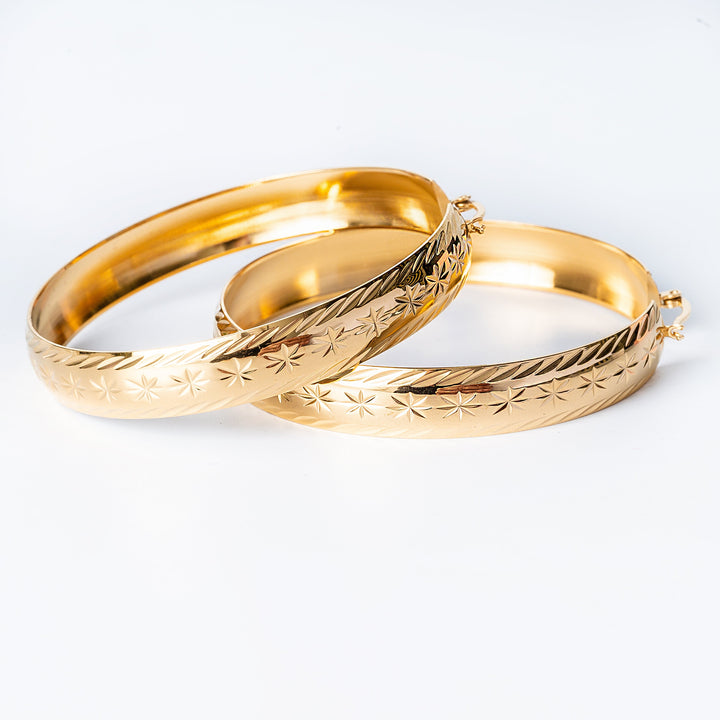 A maltese style filli earrings standing on top of each other against a white background. 