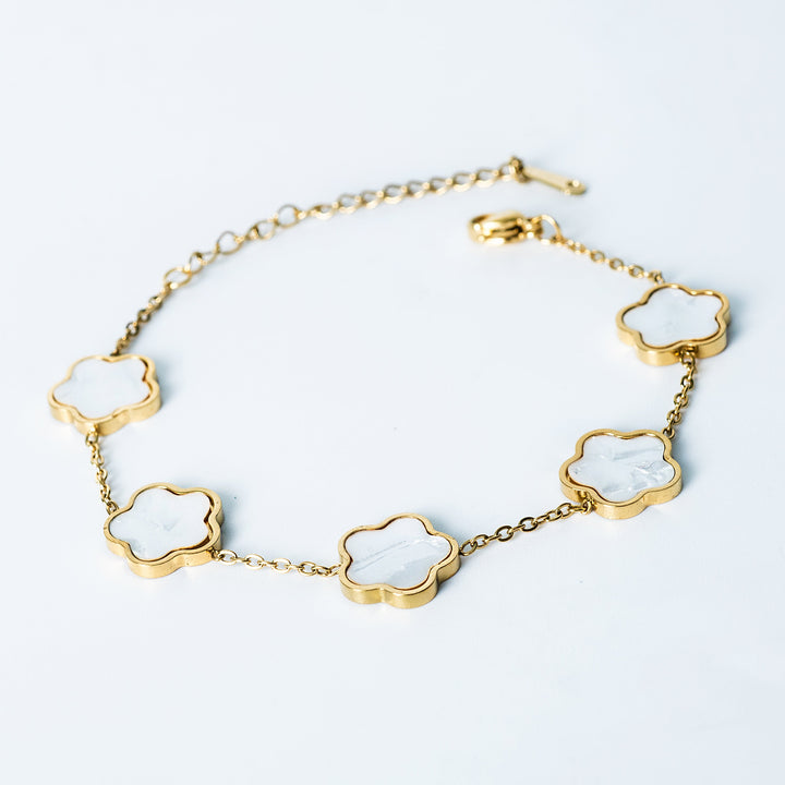 Gold Fiore bracelet featuring white mother-of-pearl flower-shaped links on a white background