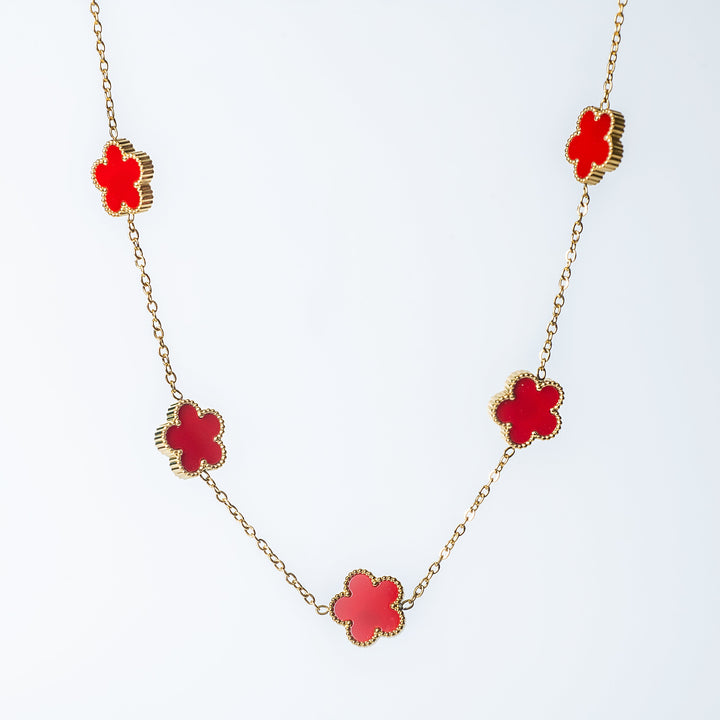 Gold Fiore necklace featuring red flower-shaped links on a white background